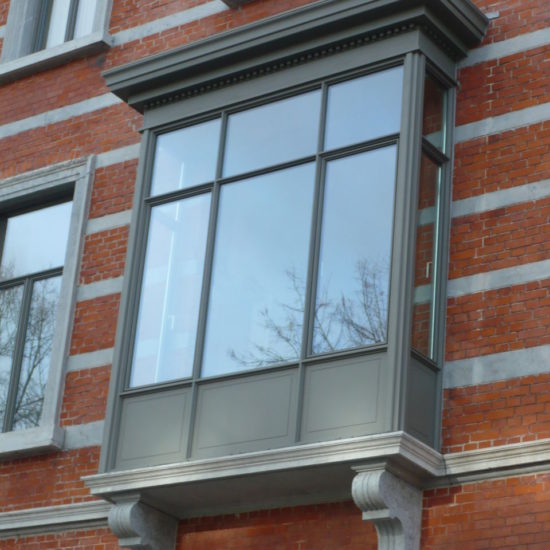 Een erker voorzien van aluminium raamprofielen van Reynaers SL38 in steel look. Het ontwerp combineert een klassiek uitstraling met moderne raamprofielen, geschikt voor renovatie. De erker is afgewerkt met een aluminium siergoot.