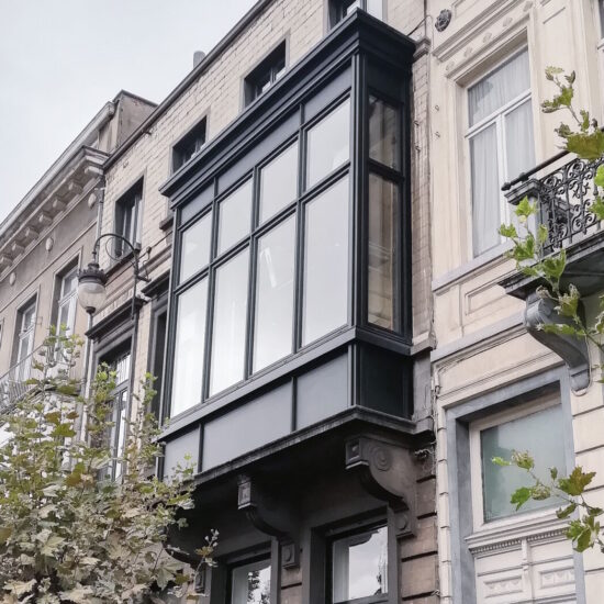 Een zwarte aluminium erker met raamprofielen van Reynaers SL38 steel look. Het ontwerp combineert een klassiek uitstraling met moderne raamprofielen, geschikt voor renovatie. De erker is afgewerkt met een aluminium siergoot.