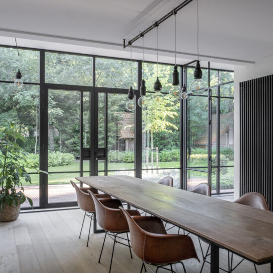 Een zwarte aluminium veranda met glas vormt een prachtige aanvulling op de woning in een klassieke stijl. De veranda wordt gekenmerkt door zwarte steel look Reynaers SL38 profielen die elegantie en tijdloze charme uitstralen. De hoge ramen en een dubbele deur zorgen voor een overvloed aan natuurlijk licht en geven een gevoel van ruimtelijkheid. Het hoge plafond draagt bij aan de grandeur en de lichte, open sfeer. De fijne en elegante gootafwerking accentueert de verfijnde details en zorgt voor een nette afwerking. De duurzame aluminium constructie en het glas zorgen voor een stijlvolle en praktische structuur. Omringd door een grote tuin vol planten en bomen, vormt deze veranda een ware oase van rust en sereniteit, perfect passend bij een klassieke en tijdloze woonstijl. Veranda Pulle